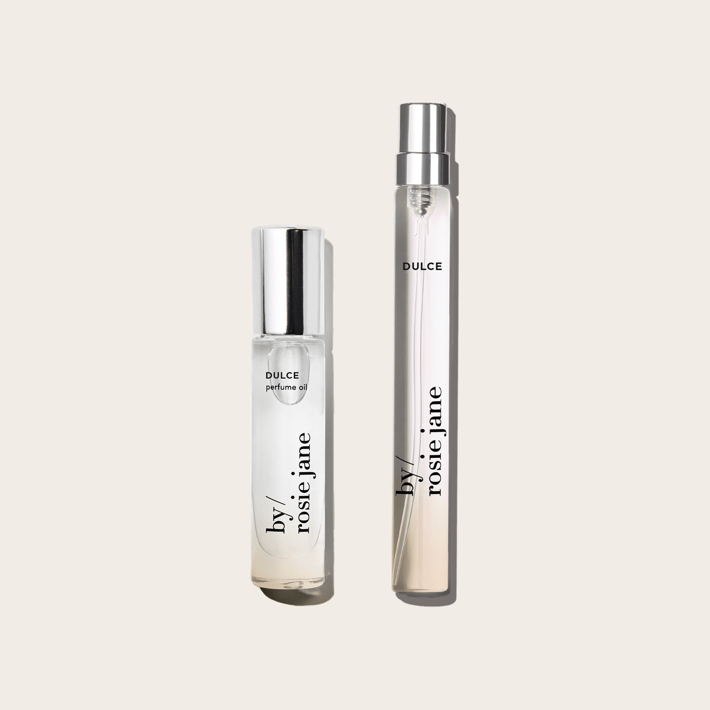 The byrosiejane DULCE 2 WAYS TRAVEL SET features a perfume oil with a white cap and a travel spray with a silver cap, side by side on a beige background. Warm vanilla and hinoki wood notes fill the air.