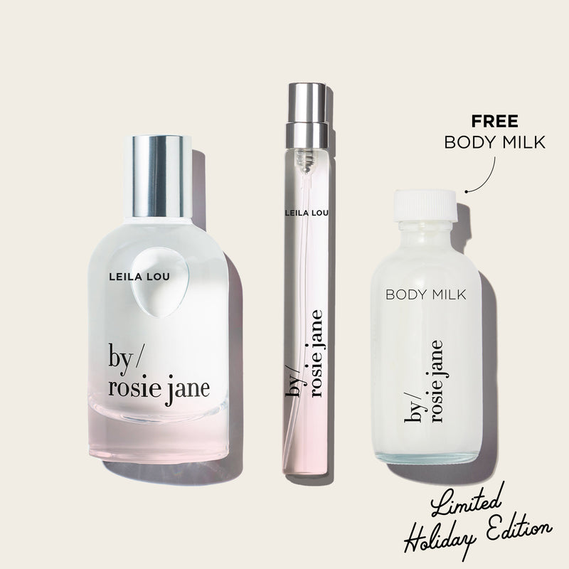 Three  LEILA LOU bottles of 'by Rosie Jane' perfume and body milk on a light beige background