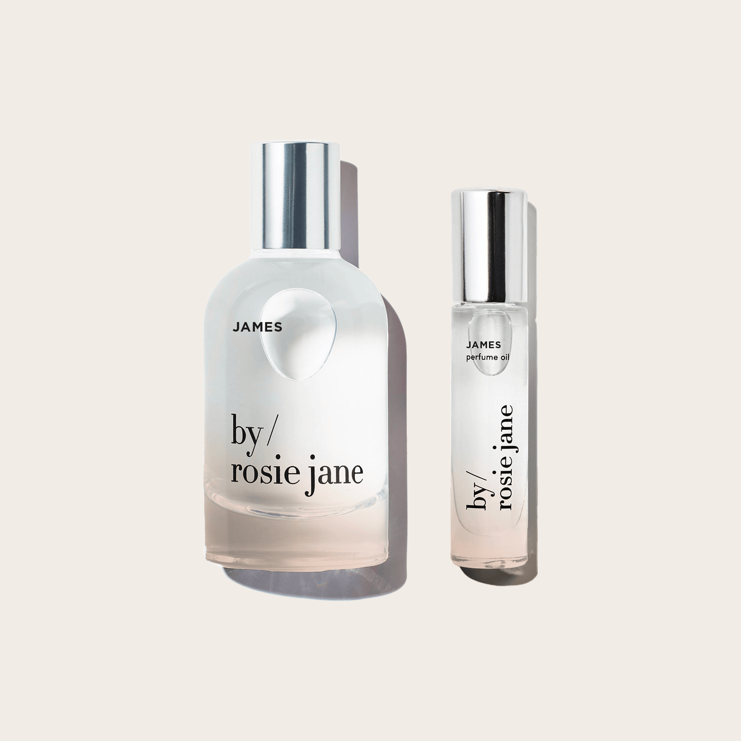 The byrosiejane JAMES LAST ALL DAY SET features two clear glass bottles—a rounded Eau de Parfum and a cylindrical Perfume Oil roller—with silver caps, displayed on a light beige background for a long-lasting fragrance.