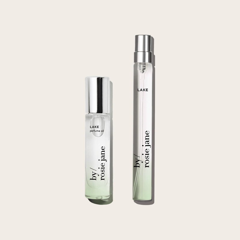 The LAKE 2 WAYS TRAVEL SET by byrosiejane features two clear glass perfume bottles—one short and wide, one tall and slim—with silver caps, displayed against a light beige background. Inspired by Lake Tahoe, its the perfect travel fragrance duo.