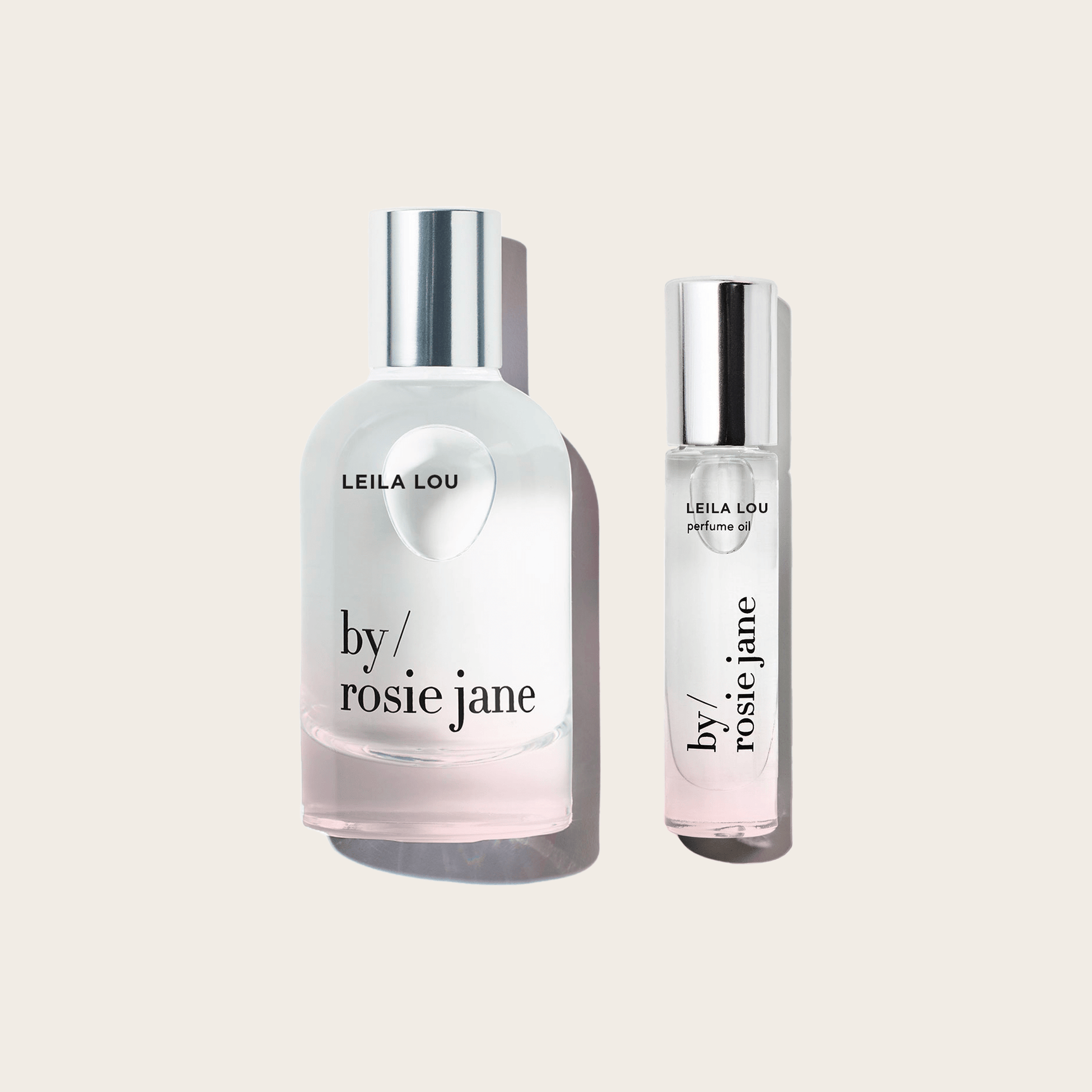 Two bottles from the byrosiejane LEILA LOU LAST ALL DAY SET are displayed on a light beige background: the larger features a rounded shape with a silver cap, while the smaller is slim, cylindrical, and also topped with a silver cap.
