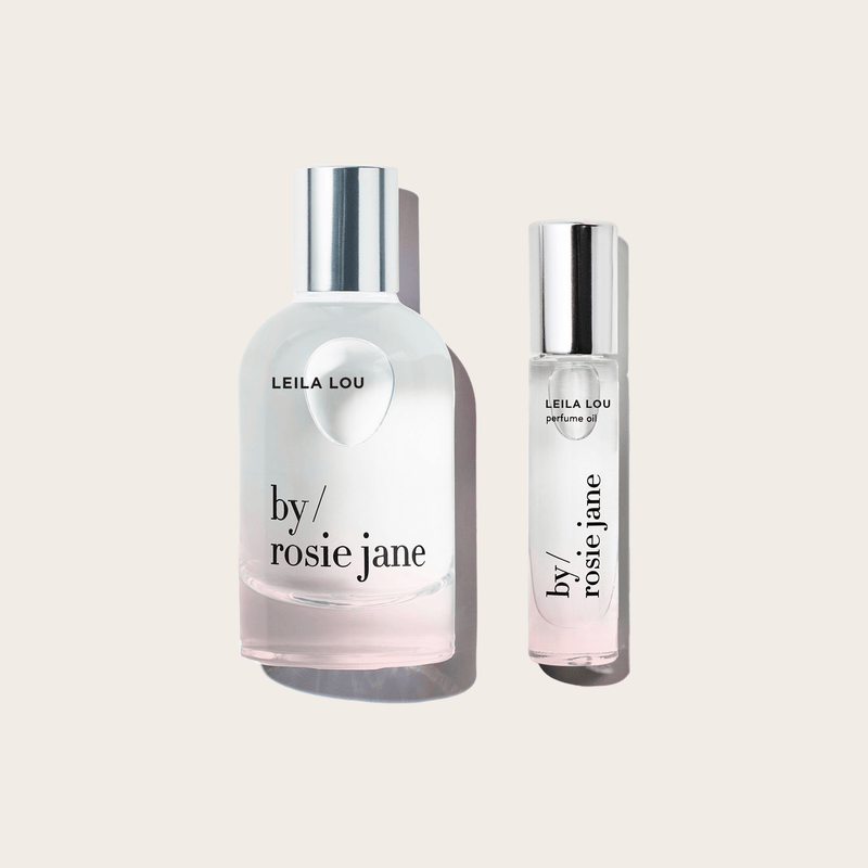 Two bottles from the byrosiejane LEILA LOU LAST ALL DAY SET are displayed on a light beige background: the larger features a rounded shape with a silver cap, while the smaller is slim, cylindrical, and also topped with a silver cap.