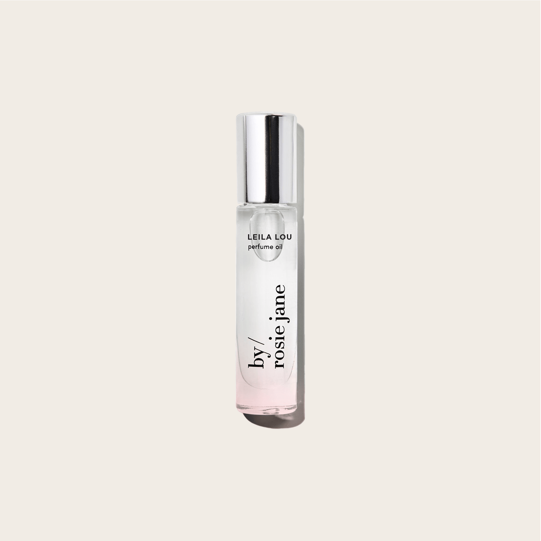 The LEILA LOU PERFUME OIL by byrosiejane sits in a clear glass bottle with a silver cap on a light beige background. Its slightly tinted oil offers an ideal everyday scent, perfectly capturing the fresh essence of spring.