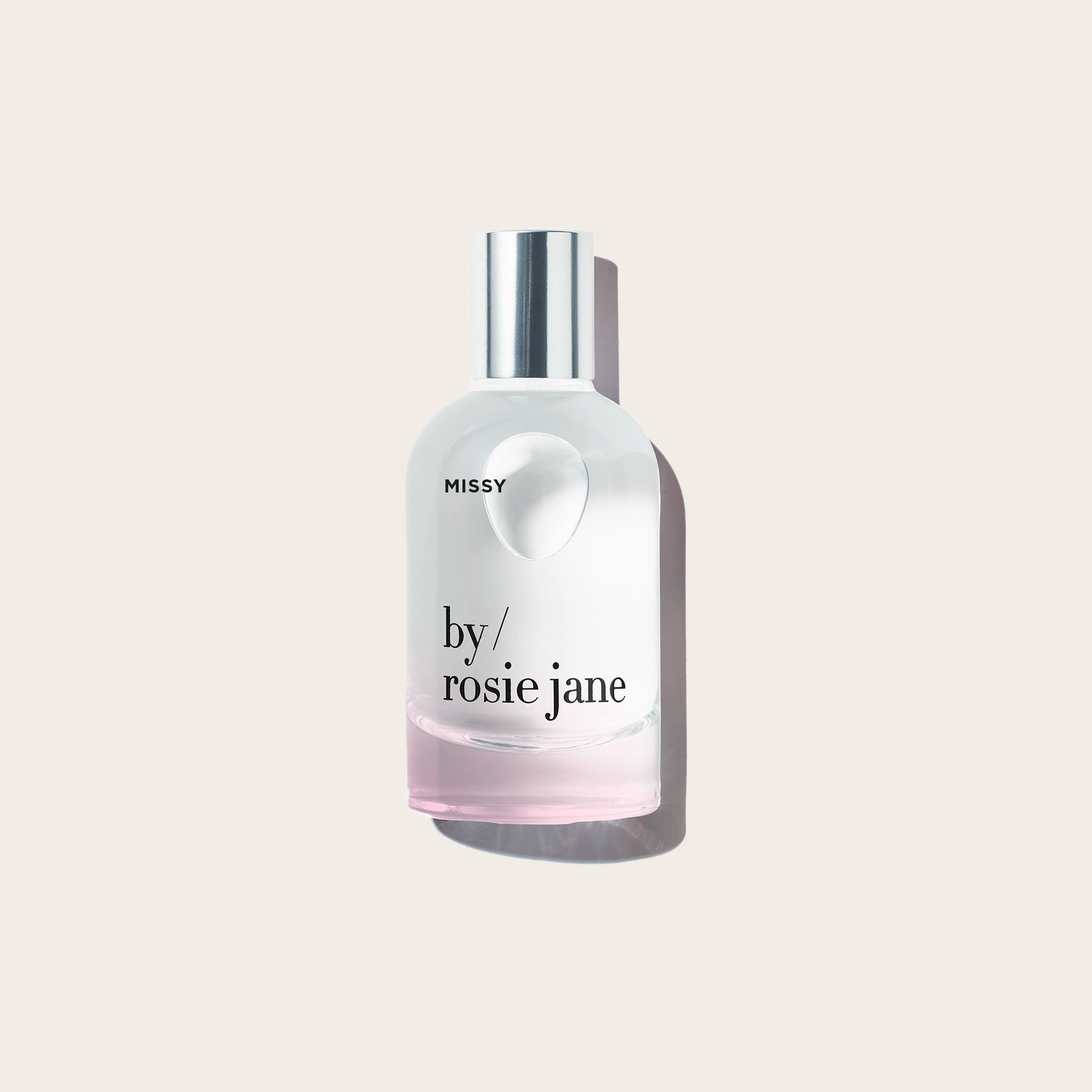 A clear glass bottle labeled MISSY PERFUME by byrosiejane with a silver cap and pale pink liquid featuring coconut notes, displayed on a light beige background with a gentle shadow.