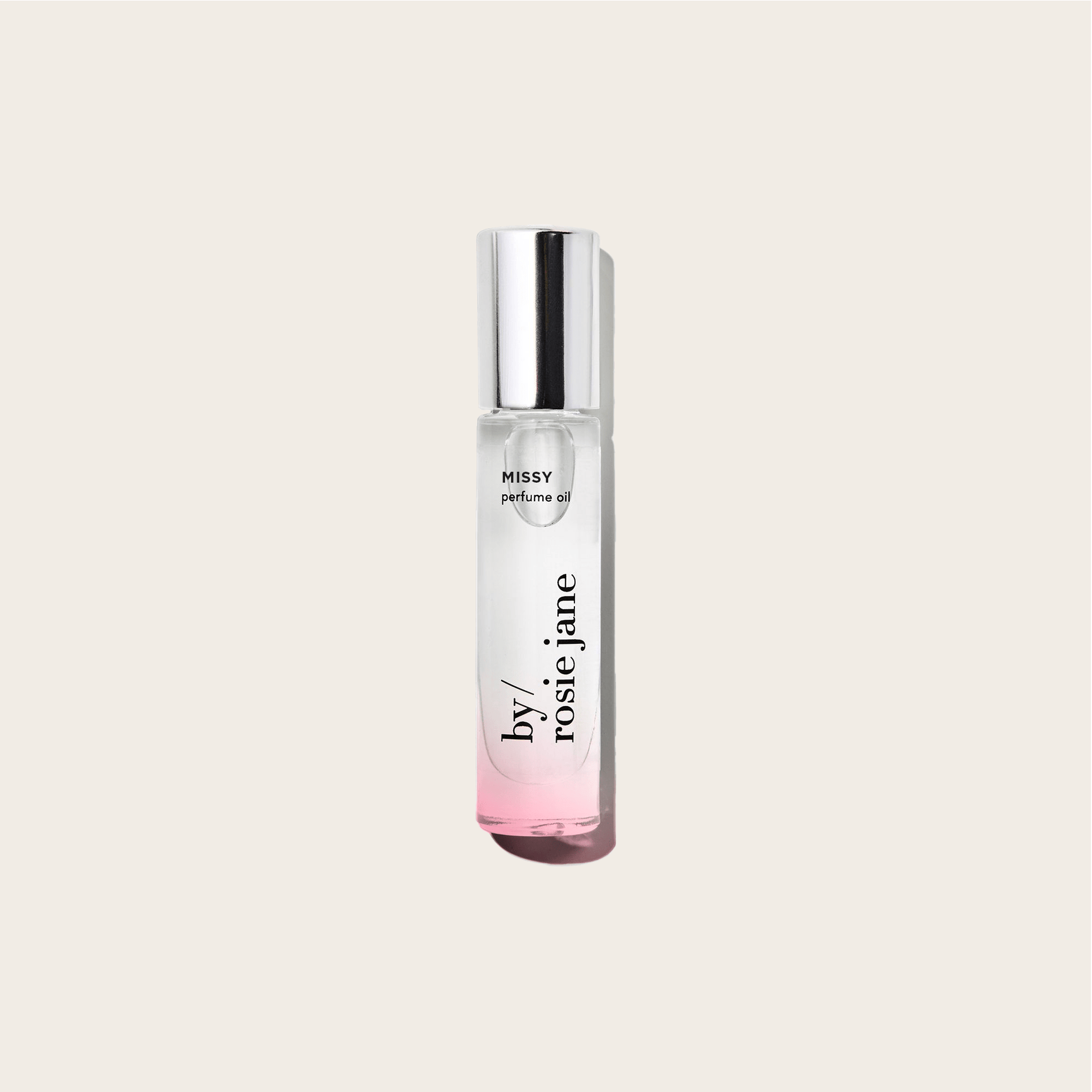 A clear glass bottle of byrosiejane MISSY PERFUME OIL with a shiny silver cap and a pink gradient base, set against a light beige background—featuring refreshing green mandarin notes.