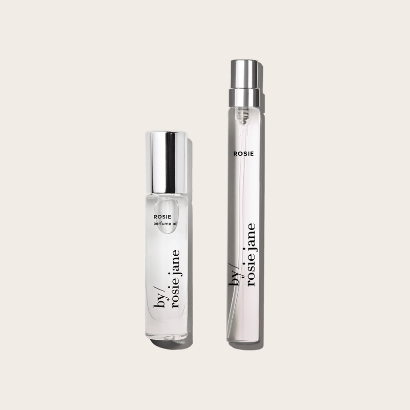 The byrosiejane 2 WAYS TRAVEL SET features two clear perfume bottles with silver caps—one perfume oil and one travel spray labeled ROSIE—displayed side by side on a light beige background.
