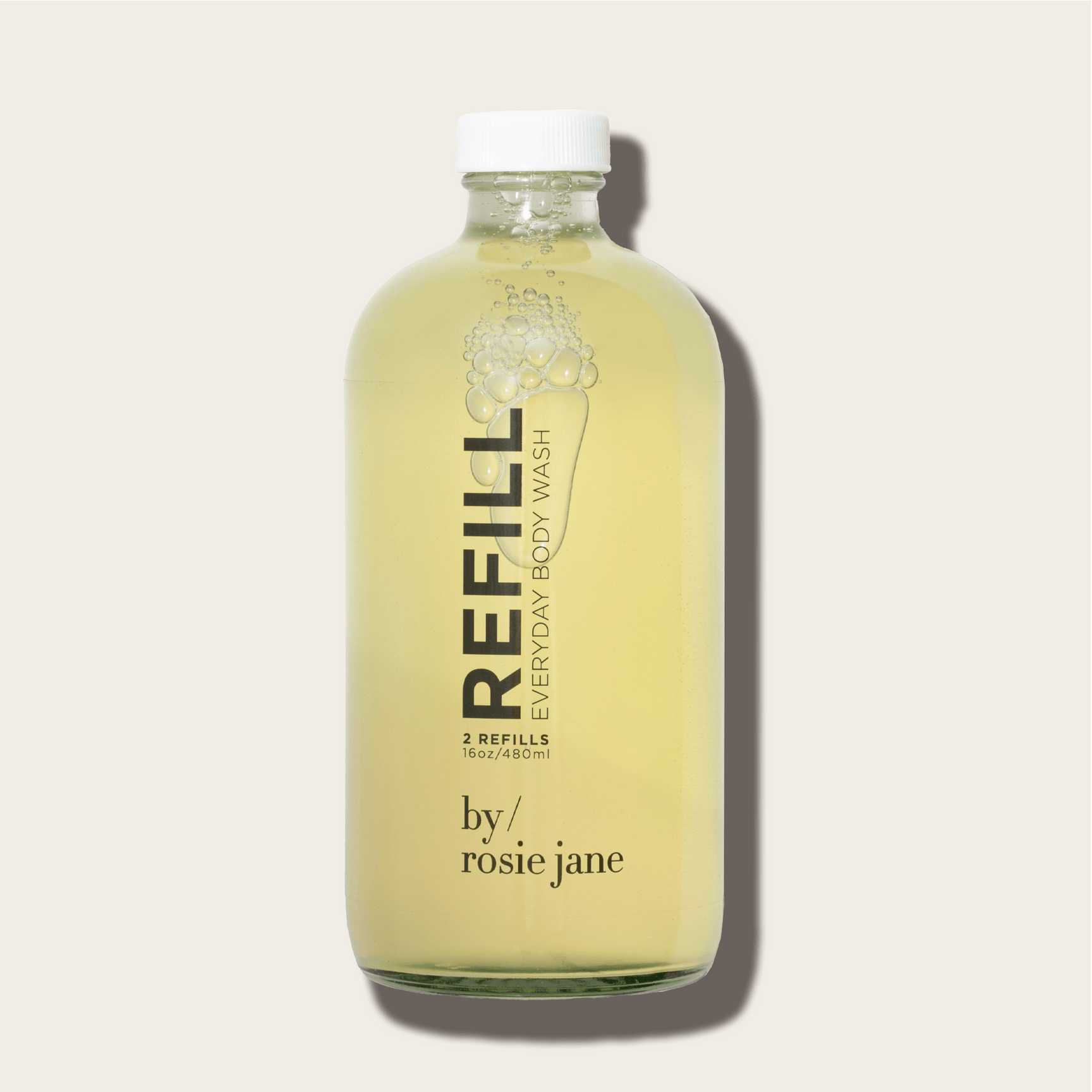 A clear glass bottle filled with yellow liquid, labeled ROSIE BODY WASH REFILL byrosiejane, sits on a light beige background. Its minimalist design features a metal cap and a formula made with organic white tea extract.