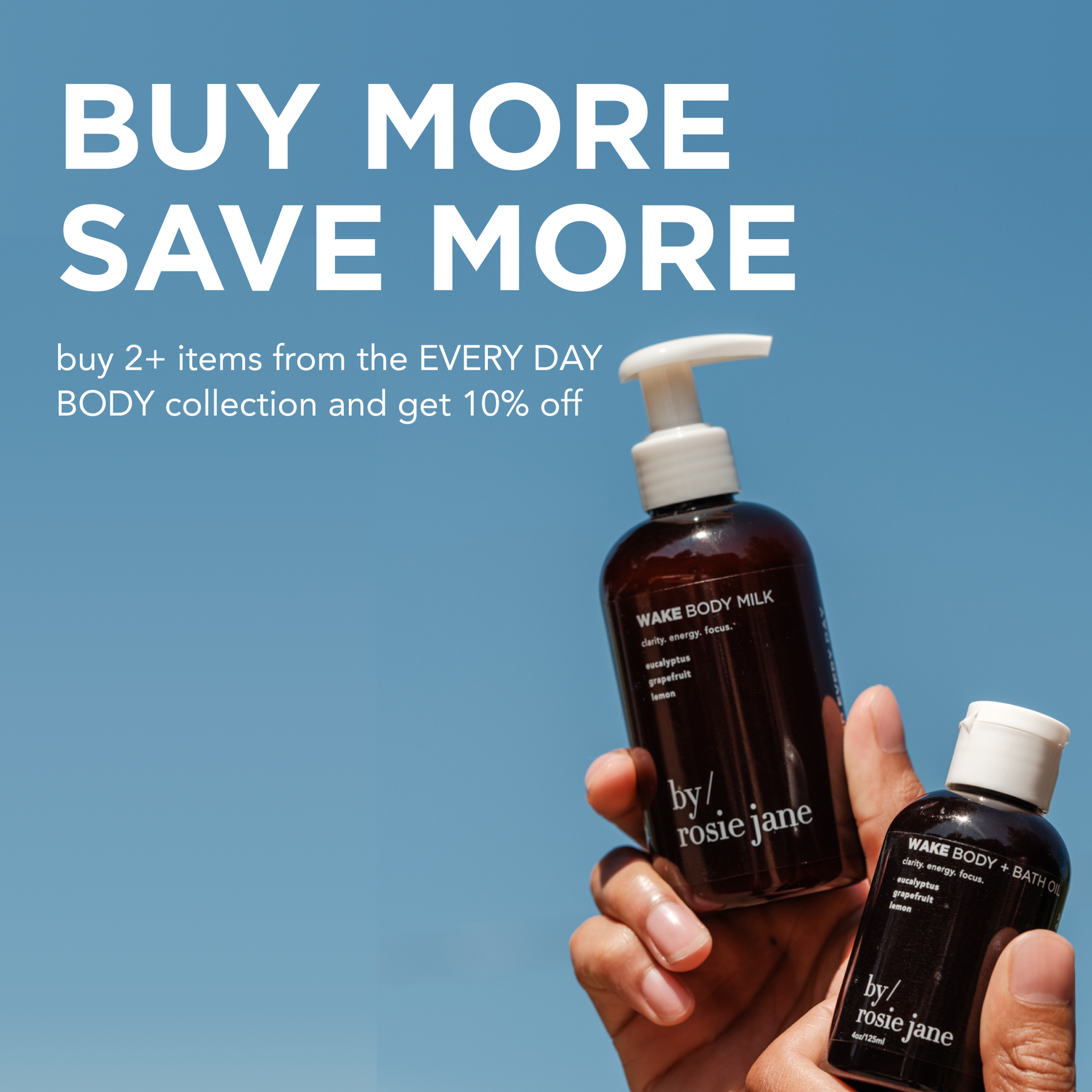 Two hands hold up dark bottles of Wake Body Milk and Wake Body + Bath Oil by rosie jane against a blue sky. Text reads: “BUY MORE SAVE MORE. buy 2+ items from the EVERY DAY BODY collection and get 10% off.”.