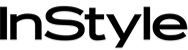 A black cat with large eyes sits upright, tail curled around its body. Its expression is alert, and its whiskers stand out against the simple, white background.
