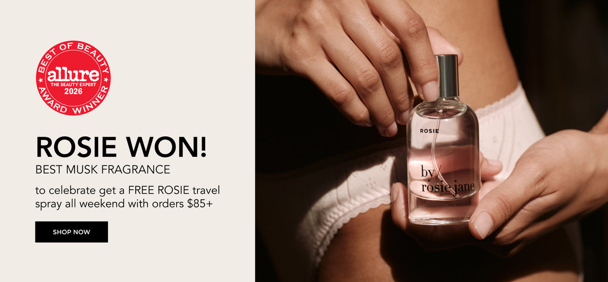 Promotional banner for Rosie Won Best Musk Fragrance, featuring a woman holding a clear glass bottle of Rosie perfume with pink liquid, alongside text and an Allure award badge.