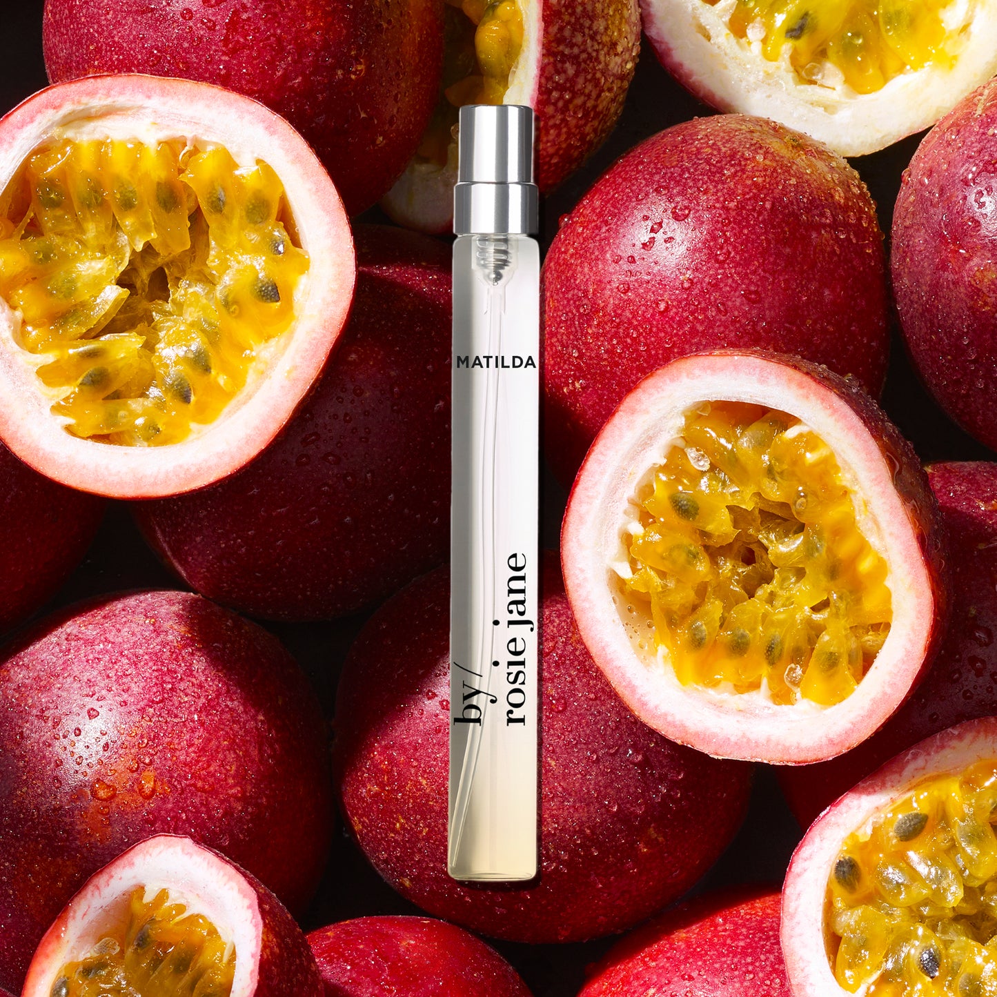 Vial of perfume with 'MATILDA' branding surrounded by halved passion fruits