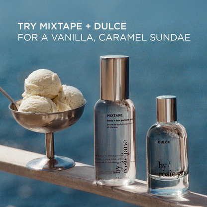 Two Rosie Jane body care products, a tall Mixtape body & hair body mist and a Dulce body wash, displayed on a wooden ledge with a bowl of vanilla ice cream in the background. Try mixtape + dulce for a vanilla, caramel sundae