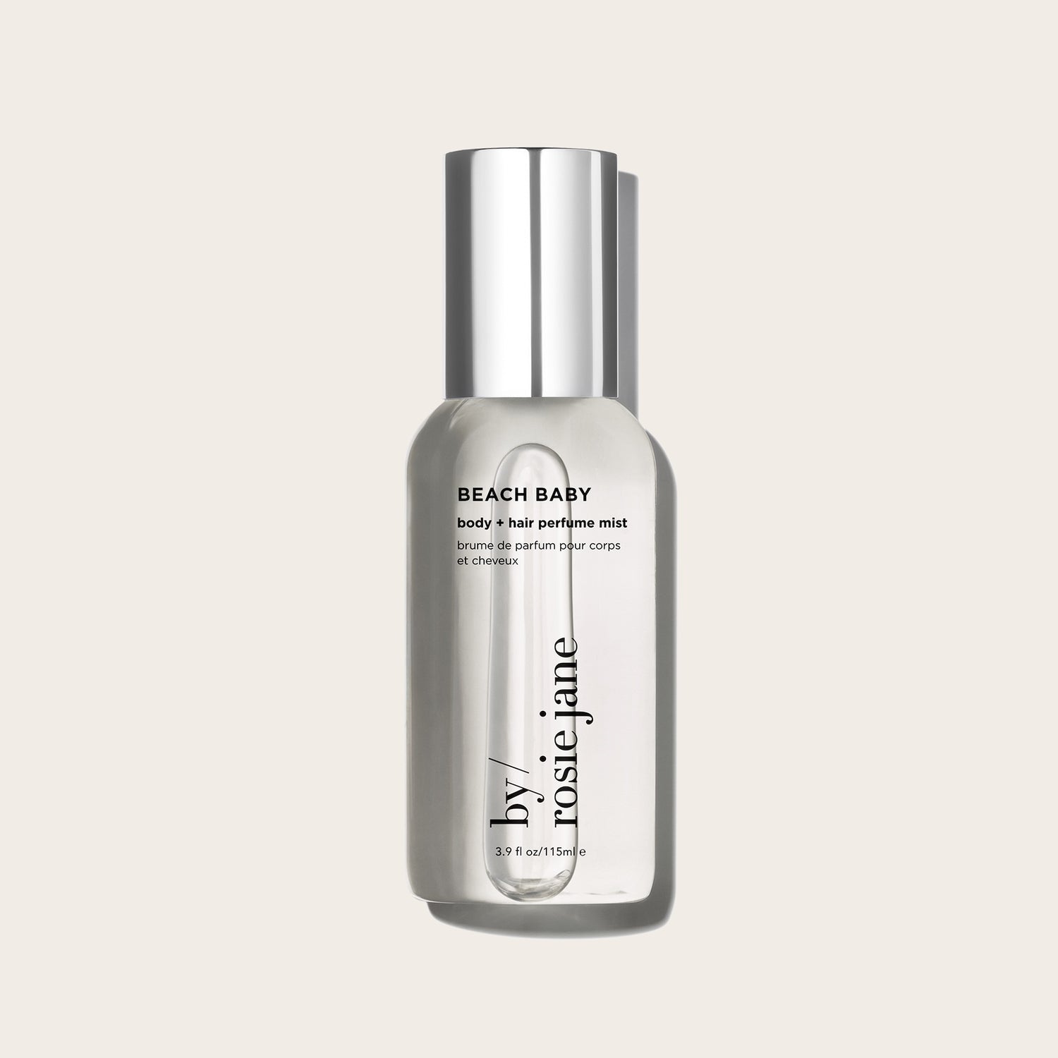 A clear bottle with a silver cap labeled BEACH BABY BODY + HAIR MIST by byrosiejane sits against a light beige background, suggesting the refreshing coconut scent for both hair and body.