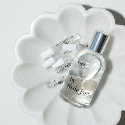 Perfume bottle labeled 'by rosie jane' on a white marble surface