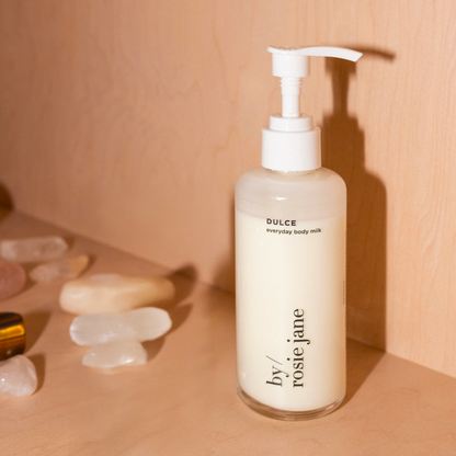 Bottle of 'Dulce' body milk by 'rosie jane' on a beige background with crystals.