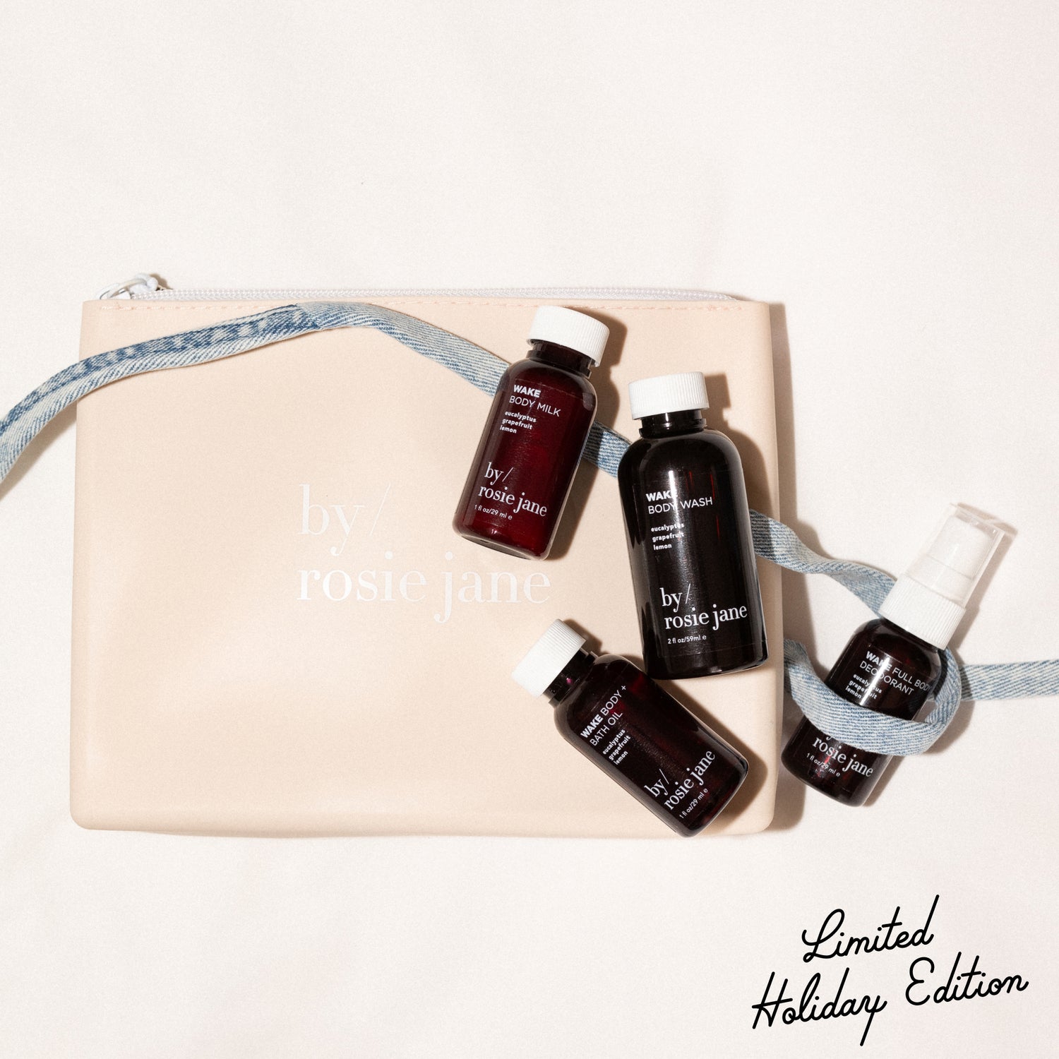 Set of mini travel size skincare products with 'by rosie jane' branding on a beige silicone bag