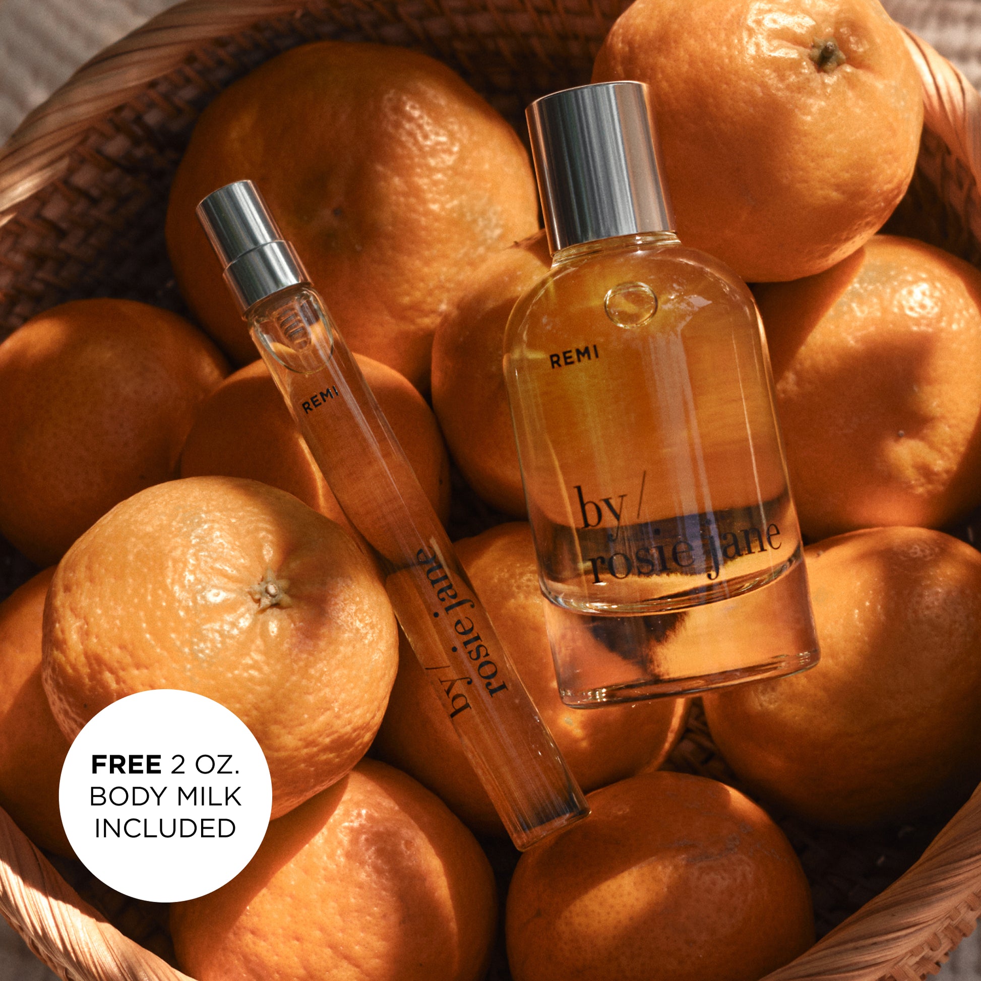 Two REMI perfume bottles on a bed of oranges with a free body milk offer.