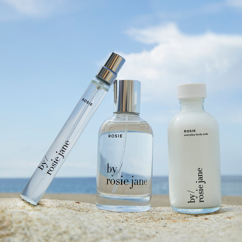 Three bottles of ROSIE 'by rosie jane' on a beach with ocean view
