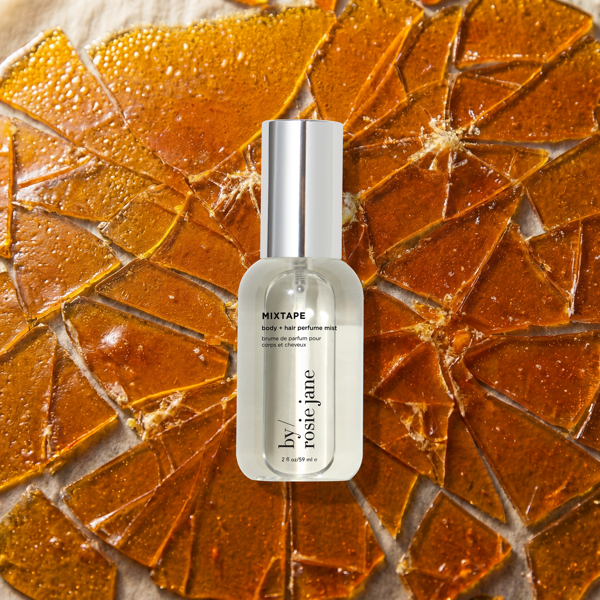 A bottle of by rosie jane body + hair mist 'MIXTAPE' stands centered against a background of broken butterscotch.