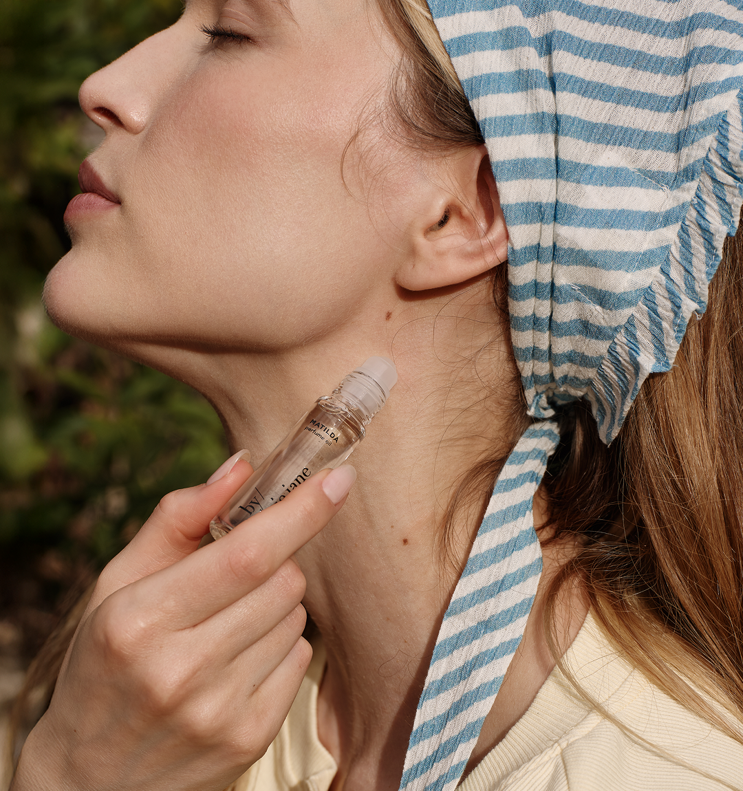 Woman applying pefume oil outdoors