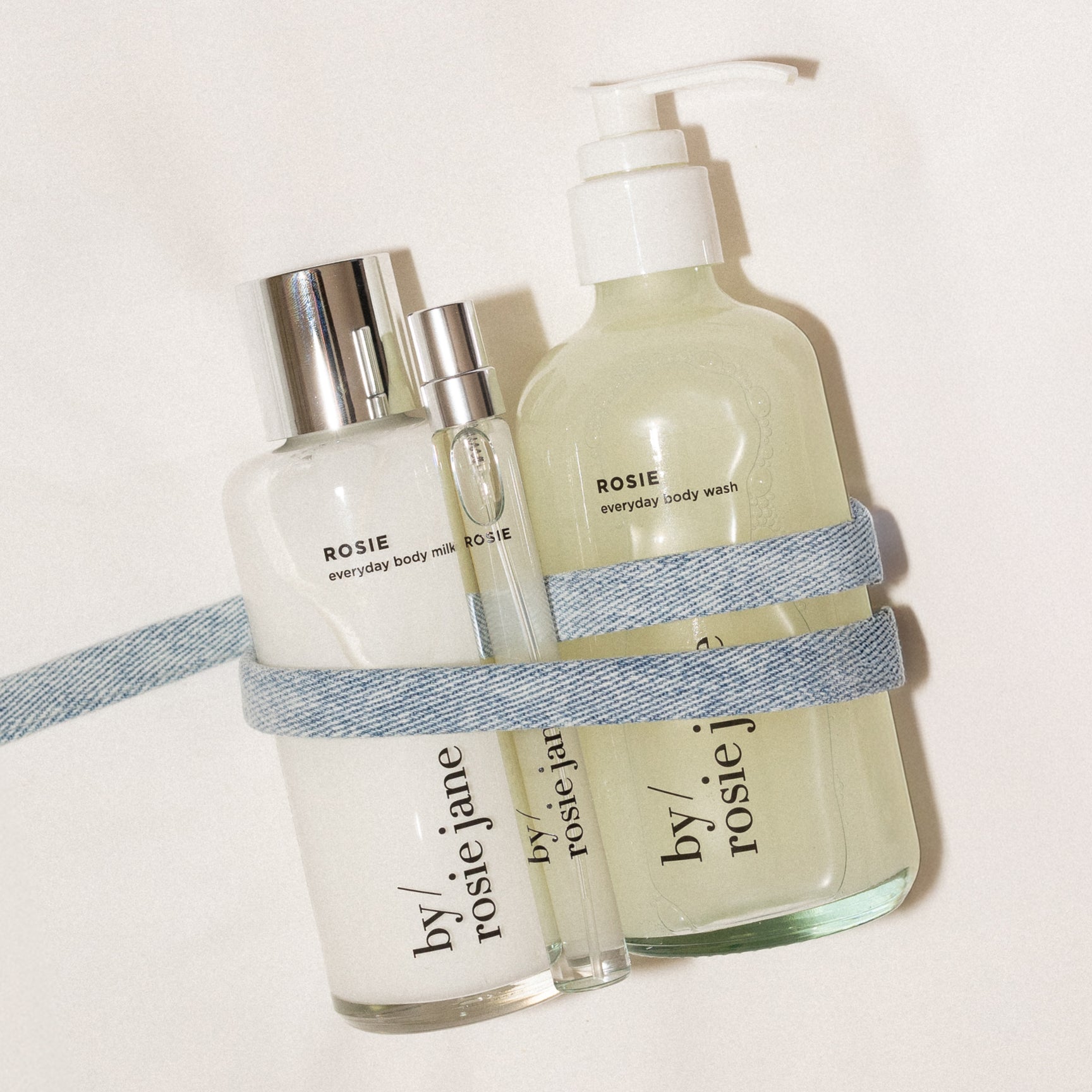 travel spray, body wash, and body milk on a light background tied with ribbon
