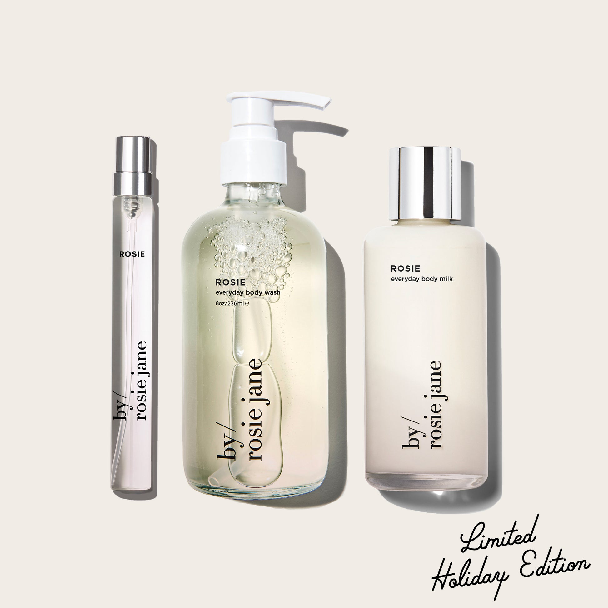 three ROSIE products, body wash, body milk, and a travel spray by 'by rosie jane' on a light beige background with 'Limited Holiday Edition' text.
