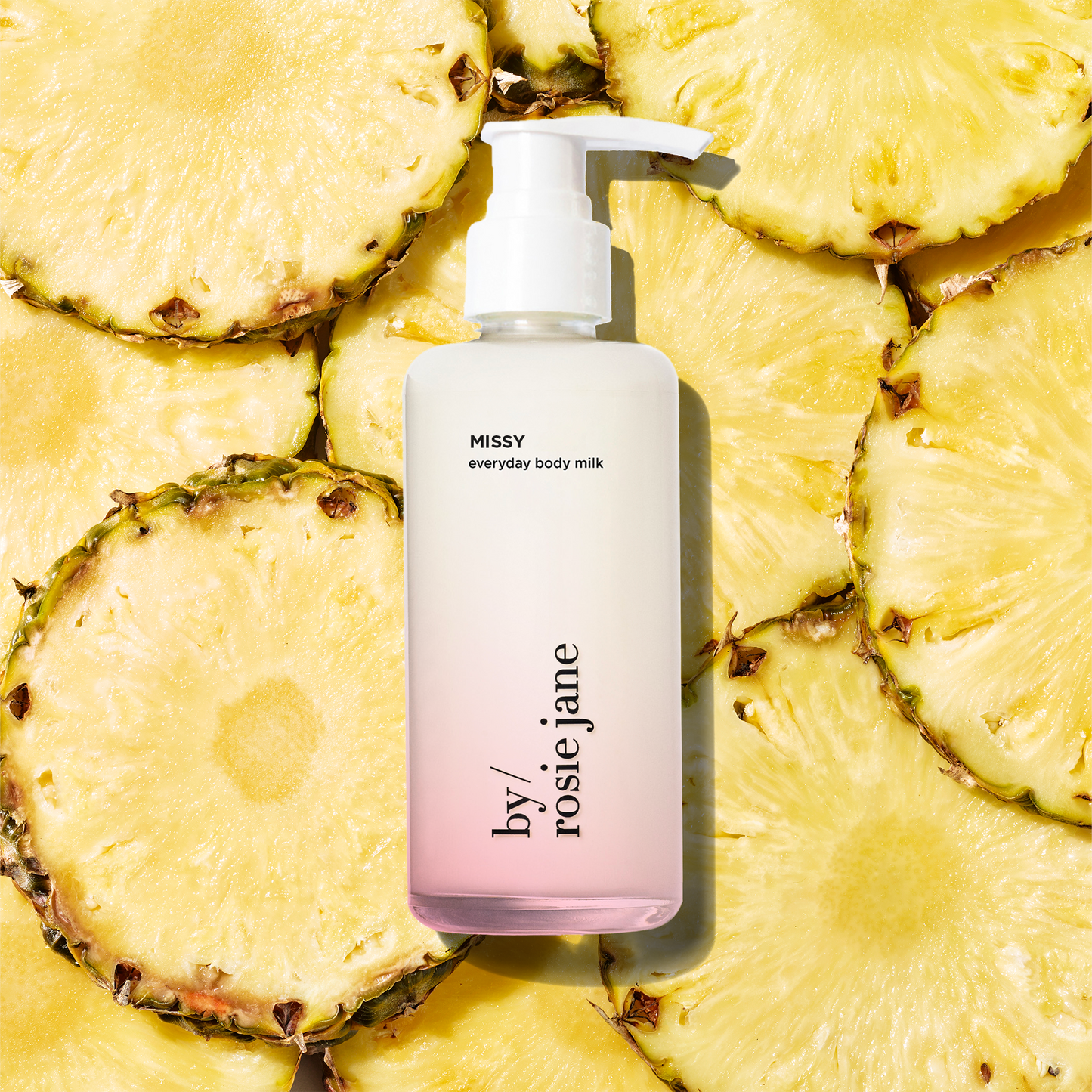 missy Body milk bottle with 'by rosie jane' branding on a background of pineapple slices