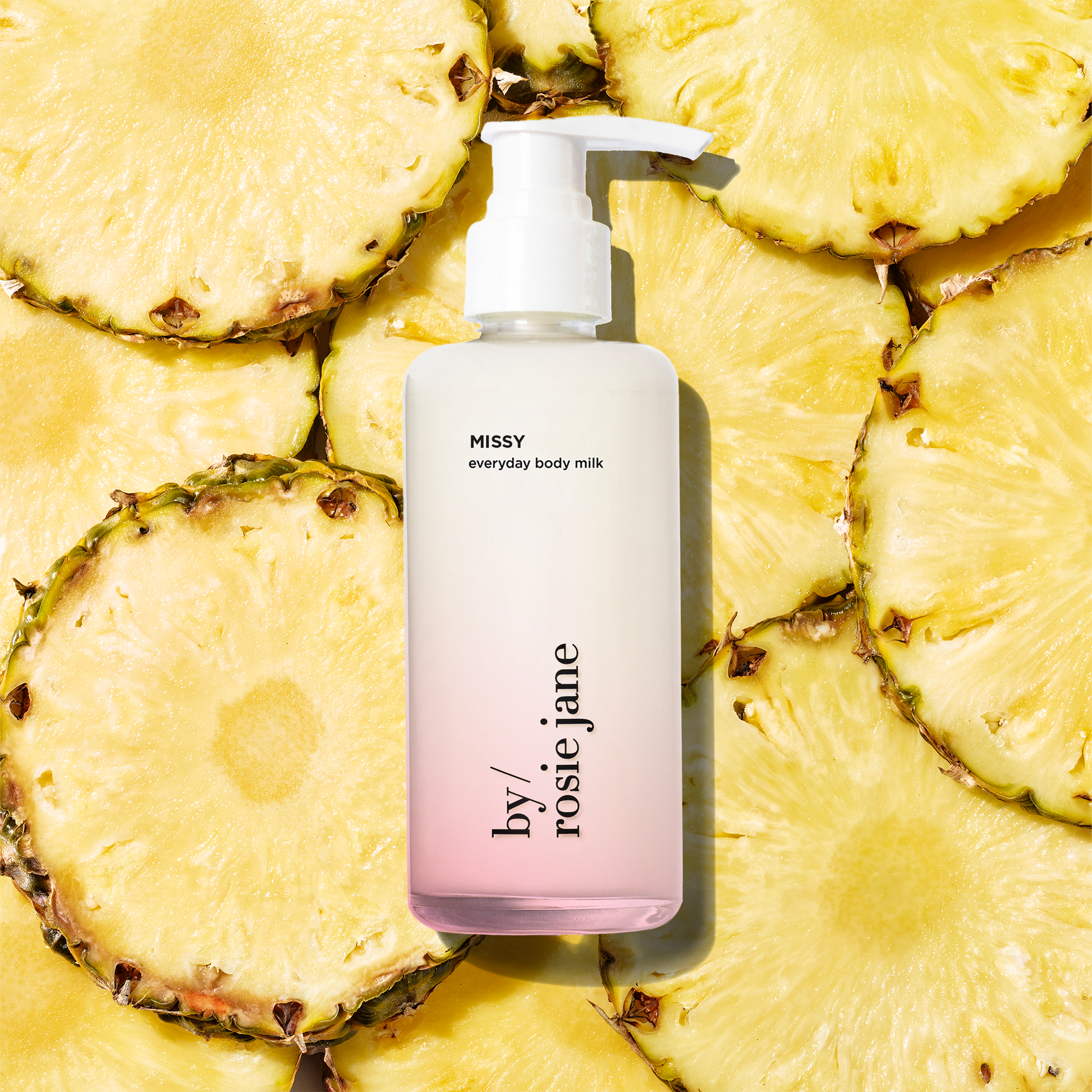 missy Body milk bottle with 'by rosie jane' branding on a background of pineapple slices