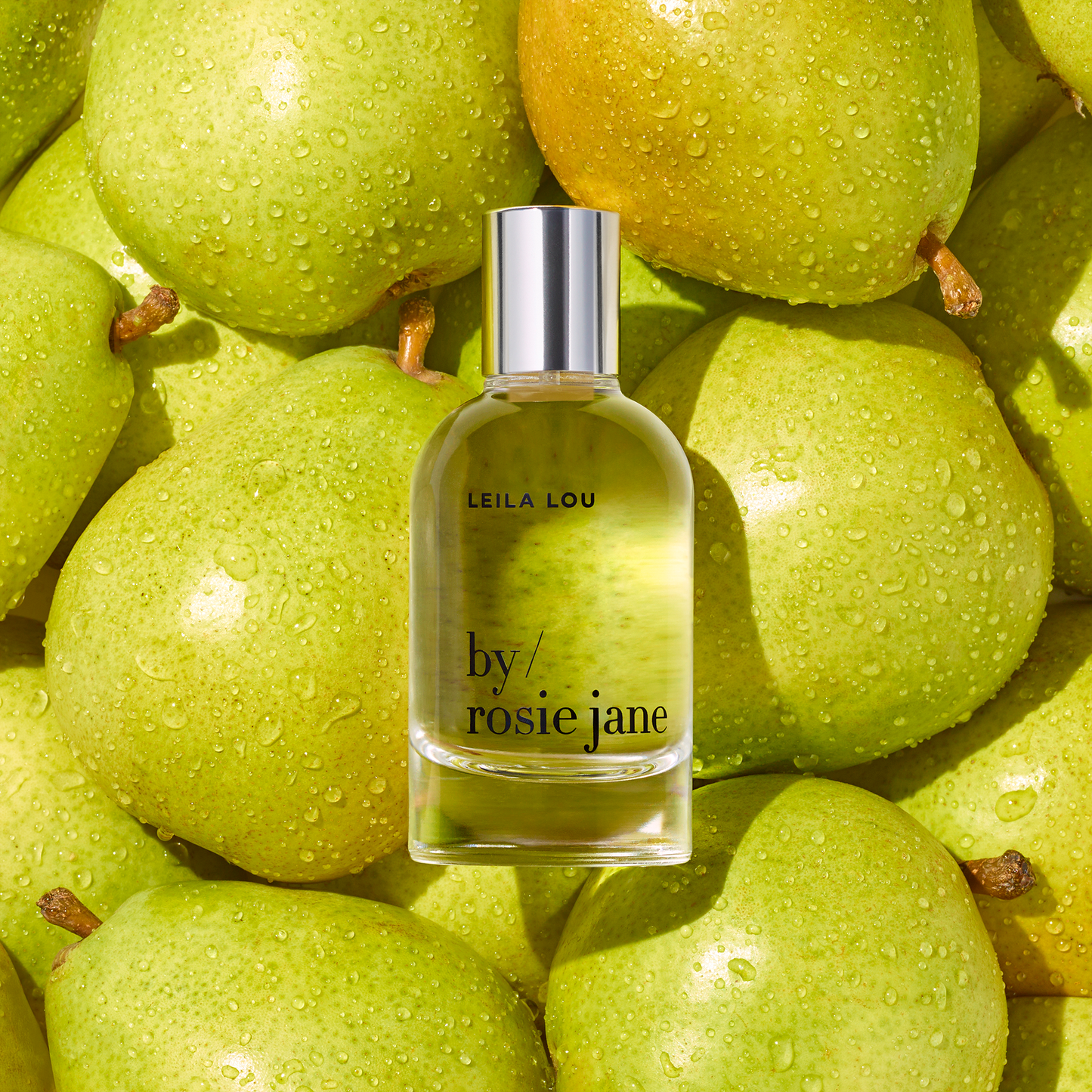 Leila Lou Everyday Body Wash bottle placed atop green pears, highlighting its fragrance notes of juicy pear, sweet jasmine, and fresh cut grass.