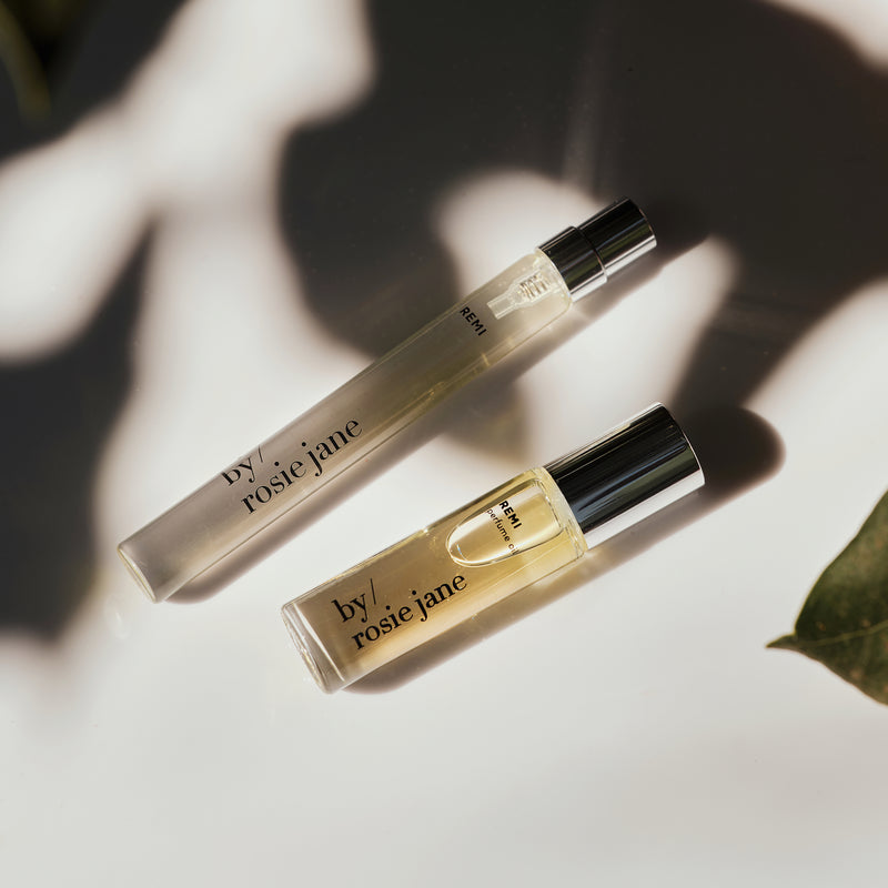 Two 'by rosie jane' perfume bottles on a counter with a leaf.