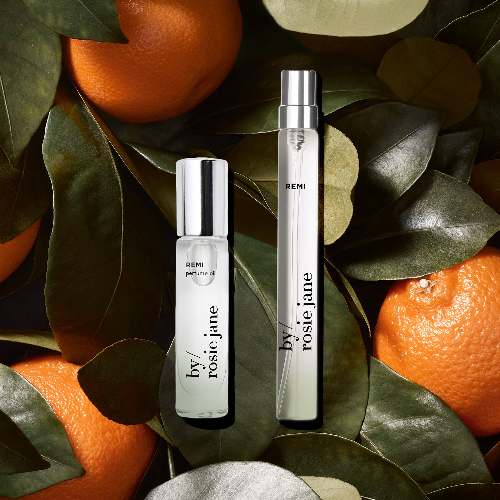 Two perfume bottles labeled 'by Rosie Jane' on a leafy background with oranges.