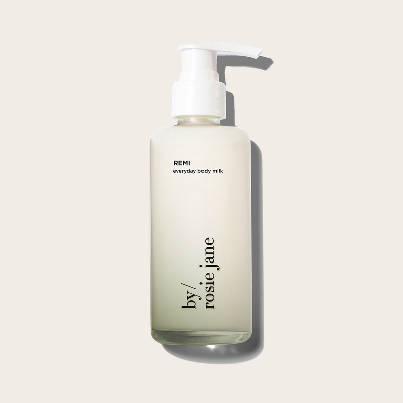 Bottle of REMI everyday body milk by rosie jane on a light beige background