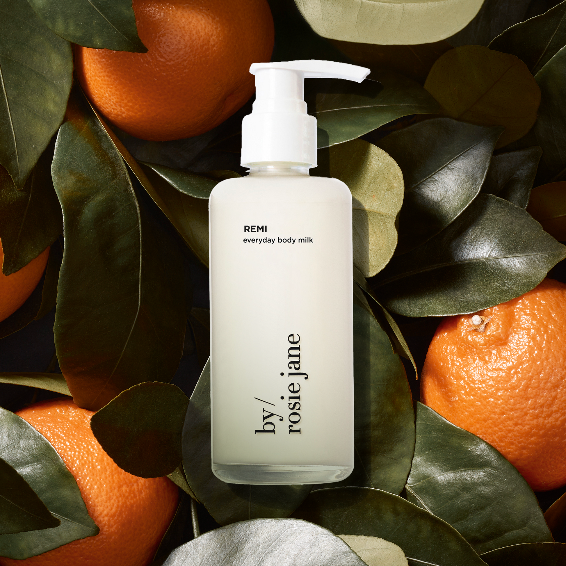 Bottle of 'REMI everyday body milk'  surrounded by oranges and leaves