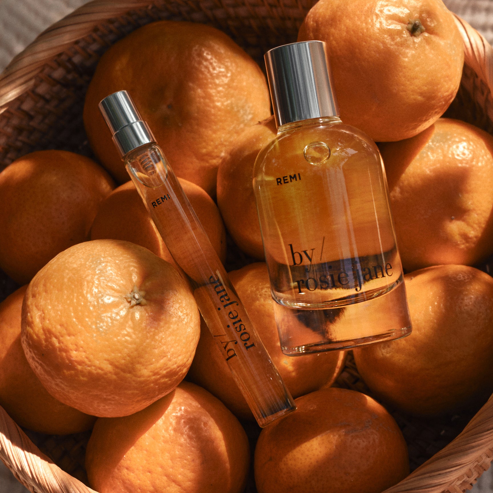 remi edp and travel spray in a basket with  mandarins