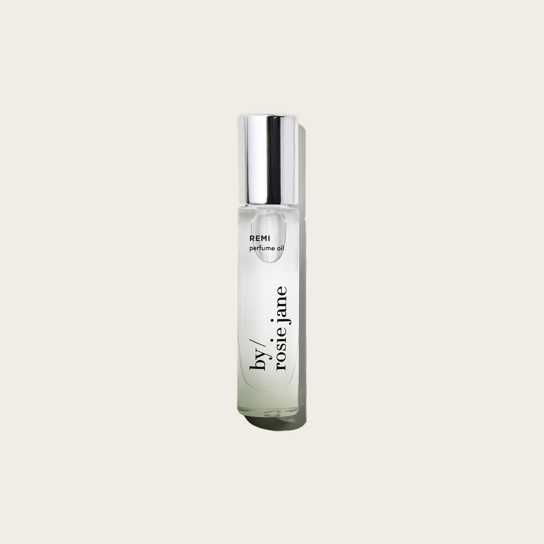 Perfume oil bottle labeled 'REMI' on a light beige background