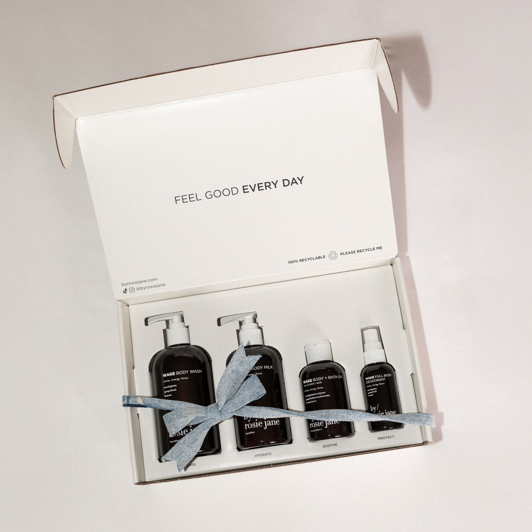 Set of brown bottles with a blue ribbon in a white box labeled 'Feel Good Every Day' on a light gray background.