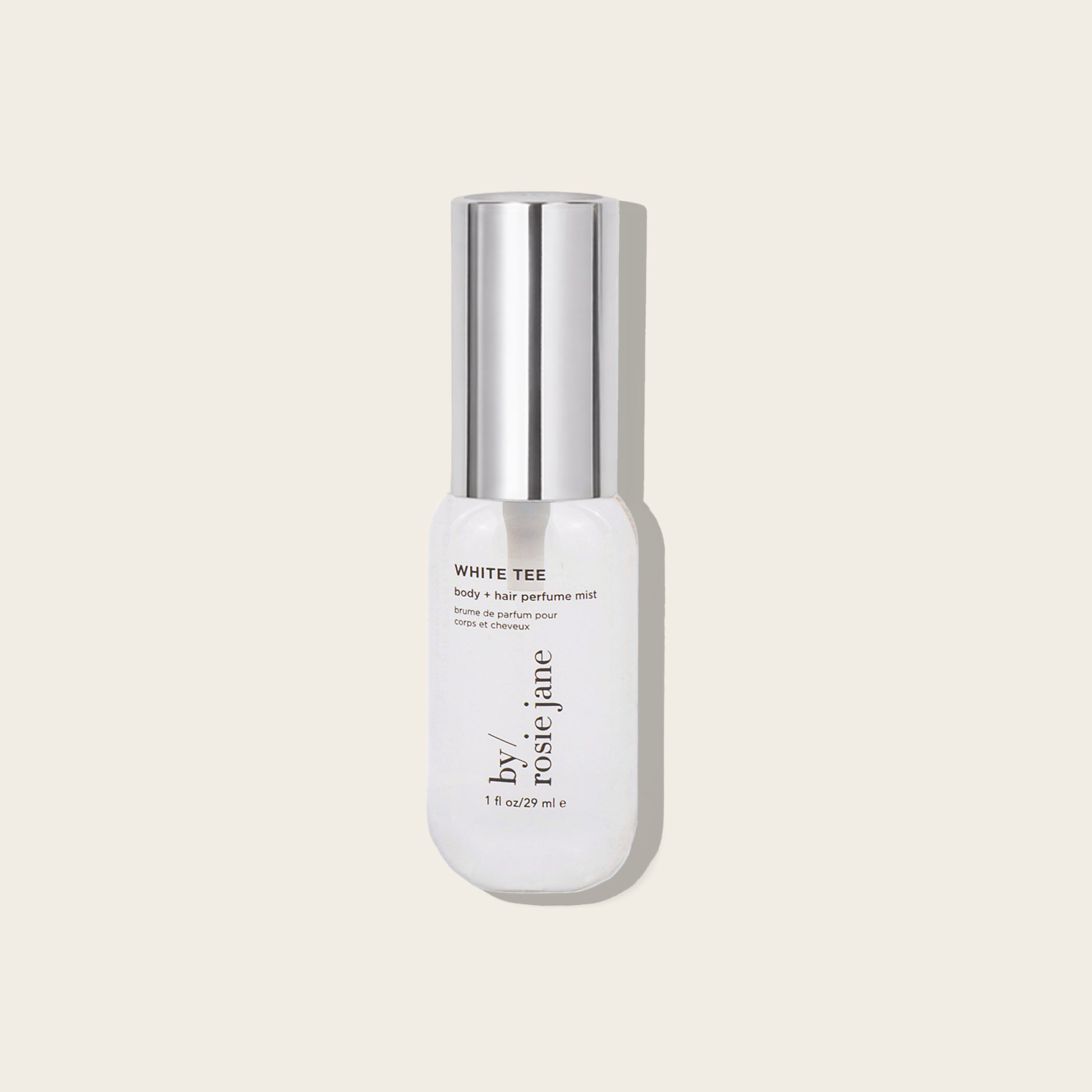 A bottle of by Rosie Jane White Tee Fortify + Hair Perfume Mist, featuring a white bottle and a reflective silver cap, set against a solid light beige background.