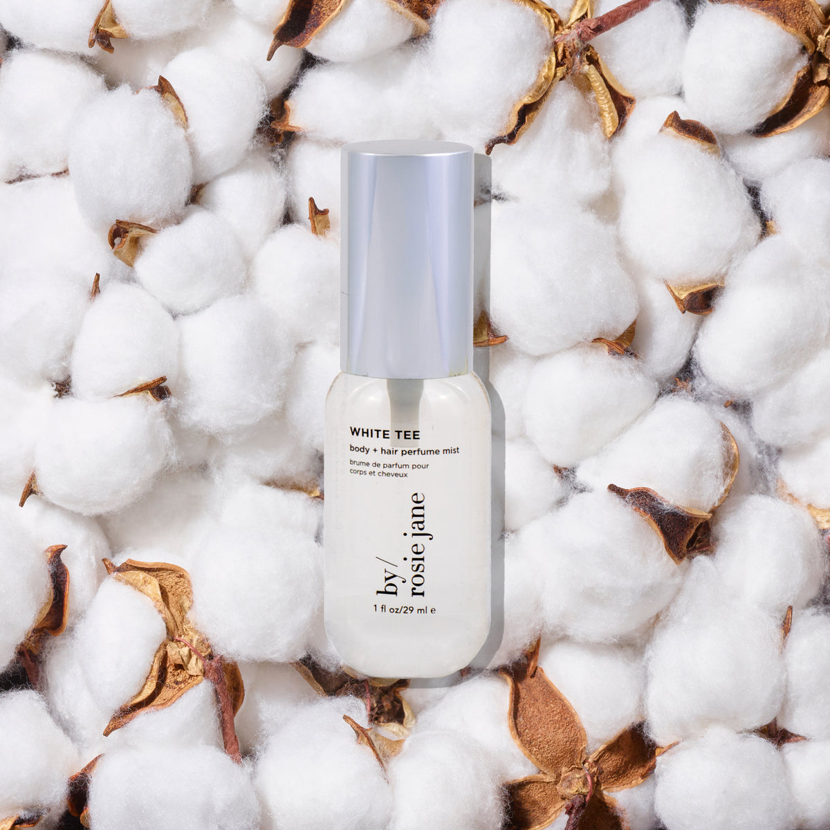 Perfume bottle labeled 'White Tee' by Rosie Jane on a bed of cotton with dried leaves.