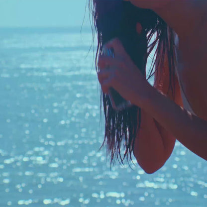 video of woman on the beach spraying body mist